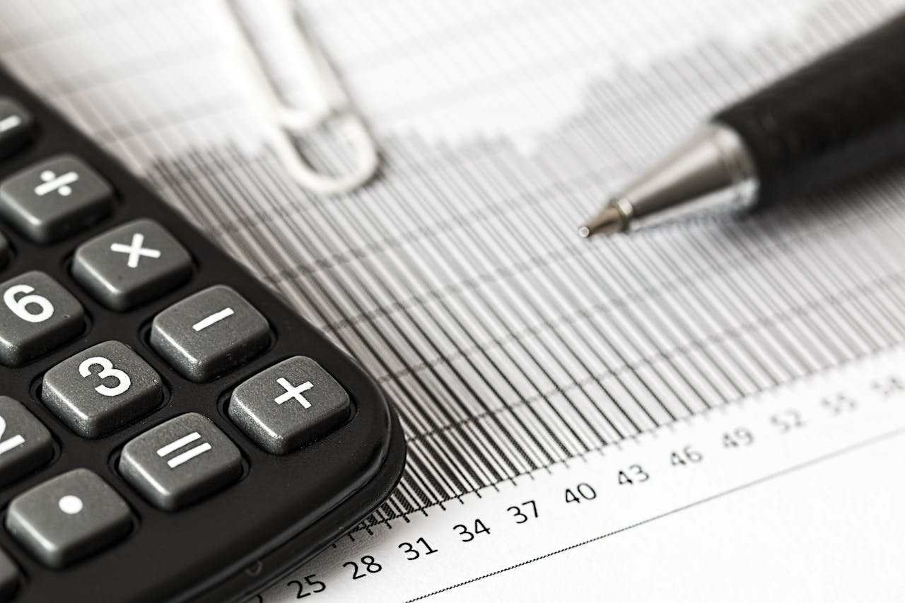 Home Close-up of a calculator and pen on a bar graph, representing finance and accounting.
